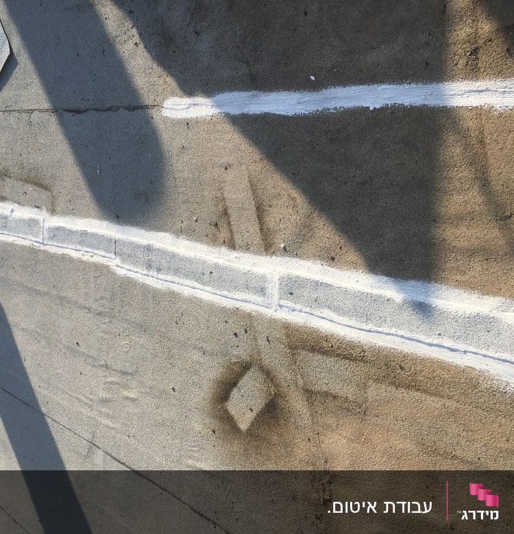 קווים לבנים של איטום על משטח בטון אפור